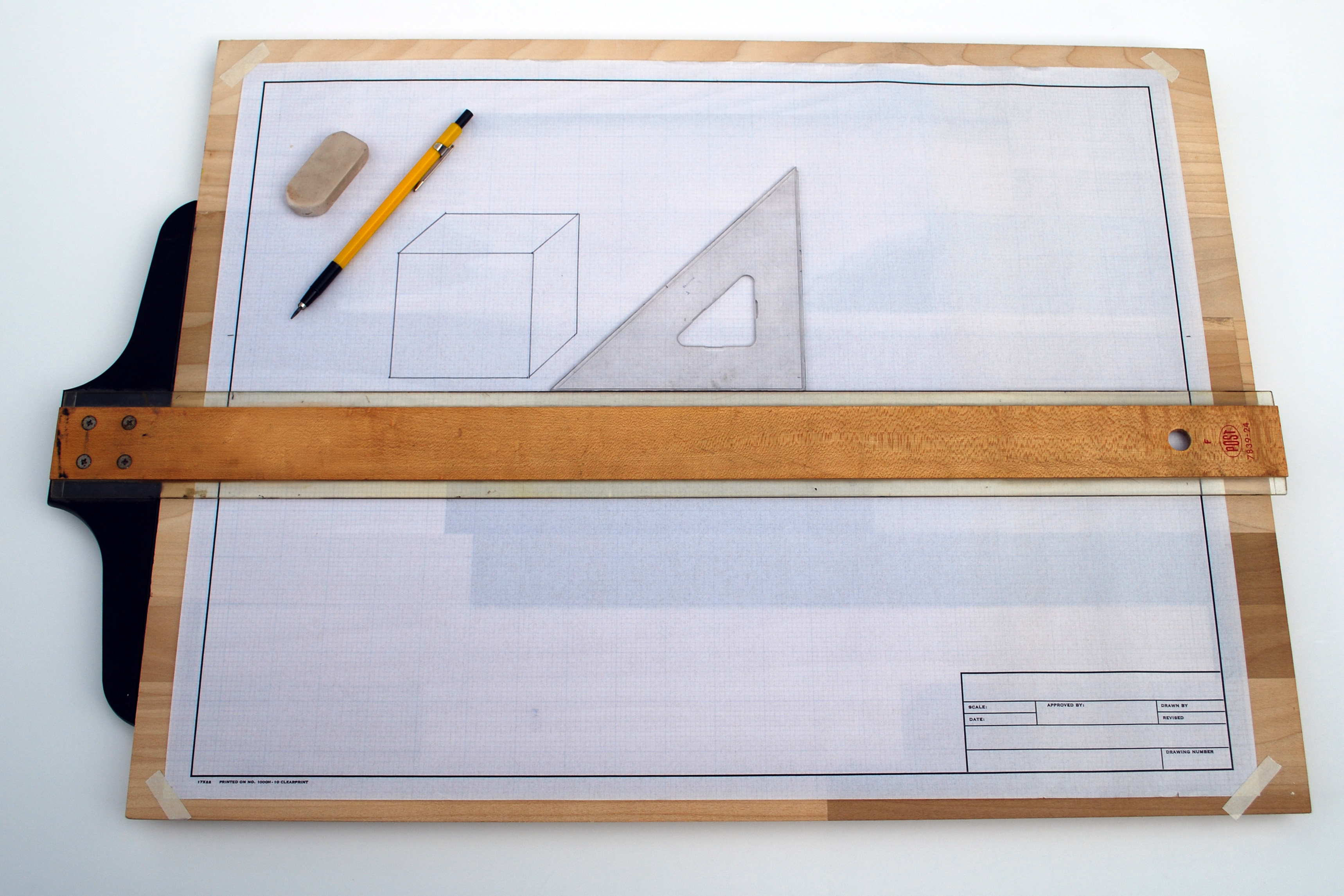 Planche à dessin : té, équerre et crayon sur une feuille quadrillée